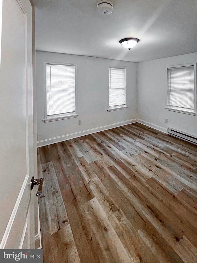 unfurnished room with a baseboard radiator, light hardwood / wood-style flooring, and a wealth of natural light