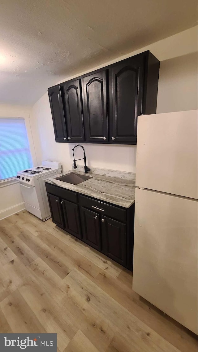 kitchen featuring sink, white appliances, and light wood-type flooring