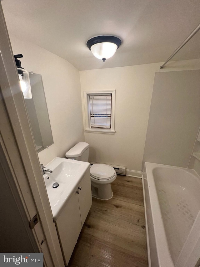 bathroom featuring a washtub, hardwood / wood-style floors, vanity, and toilet