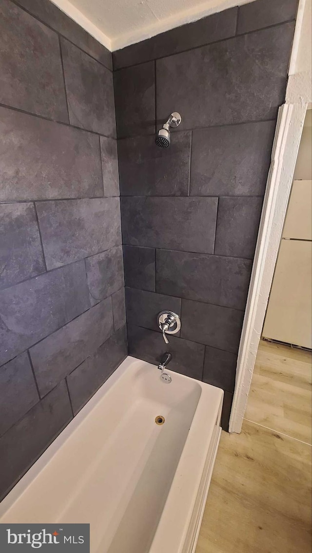 bathroom with hardwood / wood-style flooring and tiled shower / bath