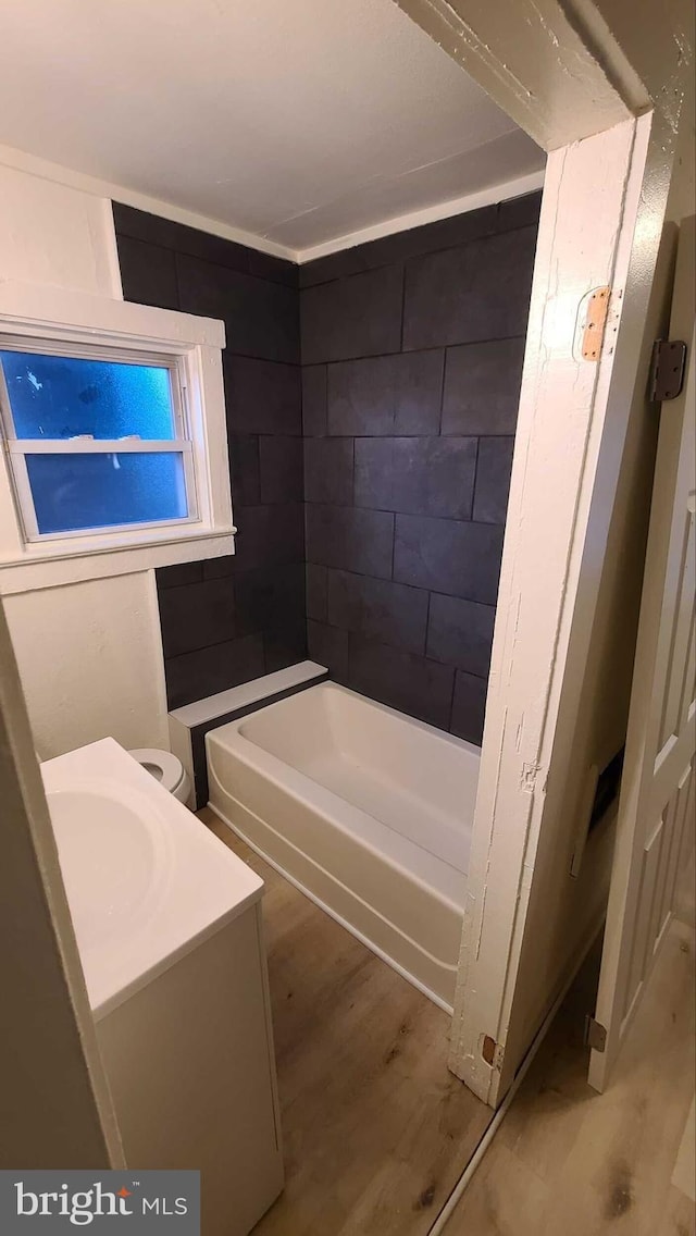 bathroom featuring vanity, toilet, wood-type flooring, and a bath