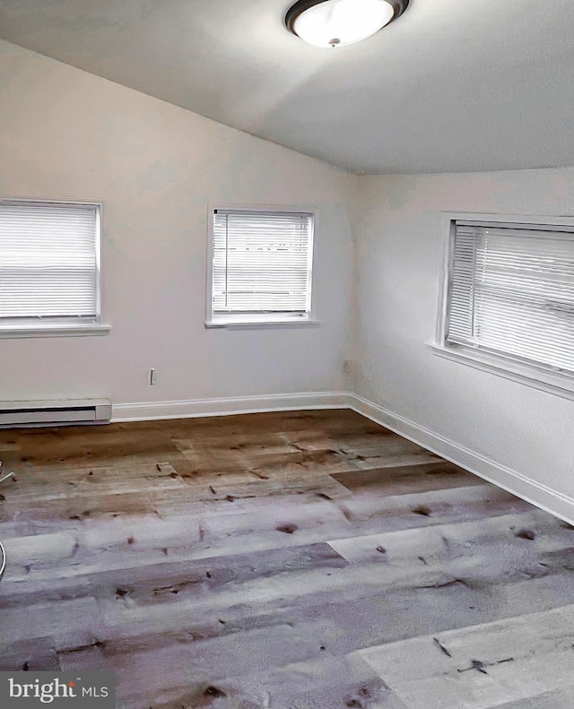 unfurnished room featuring wood-type flooring, baseboard heating, and lofted ceiling