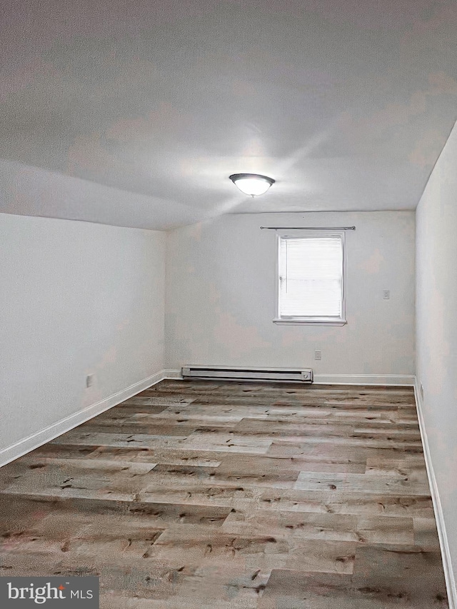 empty room featuring vaulted ceiling, a textured ceiling, a baseboard radiator, and light hardwood / wood-style flooring