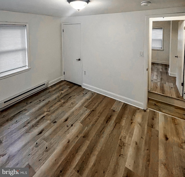 unfurnished room with dark hardwood / wood-style floors and a baseboard heating unit