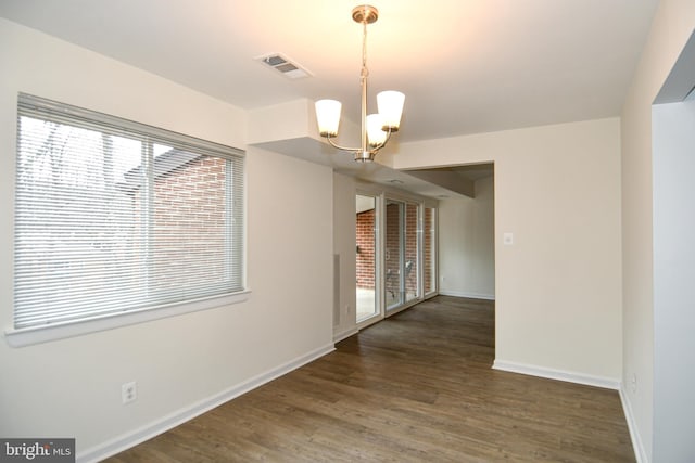 unfurnished room featuring a chandelier, wood finished floors, visible vents, and baseboards