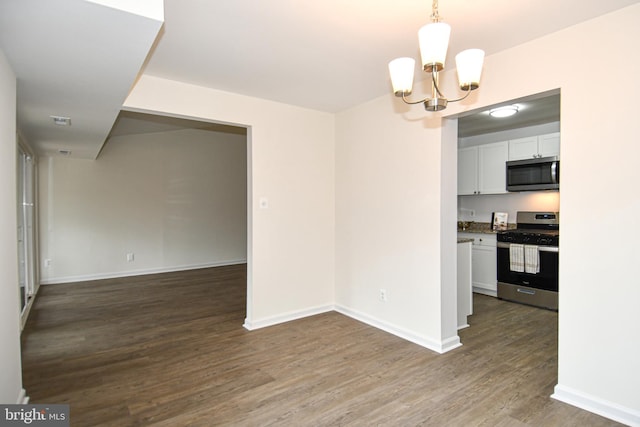 unfurnished dining area with a chandelier, visible vents, baseboards, and wood finished floors