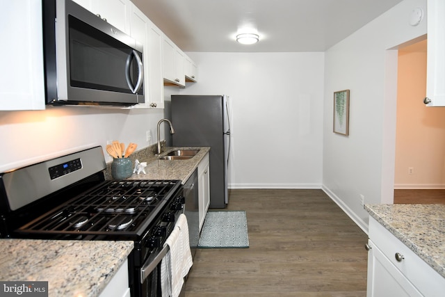 kitchen featuring baseboards, white cabinets, light stone counters, dark wood-type flooring, and stainless steel appliances