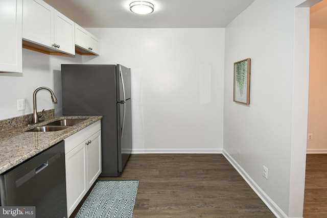 kitchen with white cabinets, dark wood finished floors, dishwashing machine, light stone countertops, and a sink