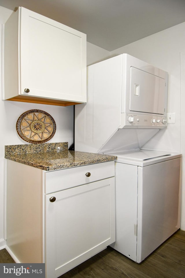 laundry room with laundry area, dark wood-type flooring, and stacked washer / drying machine