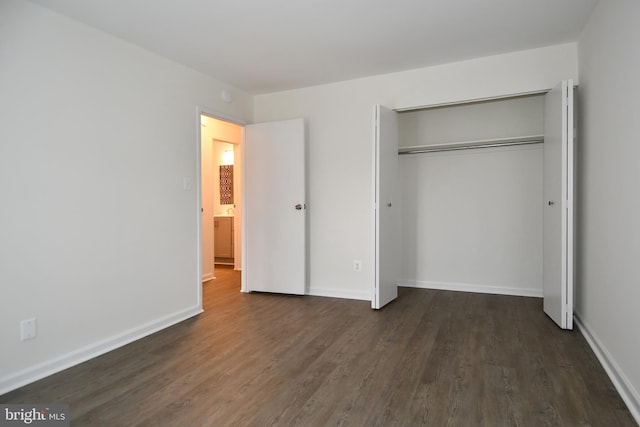 unfurnished bedroom with a closet, baseboards, and dark wood-style flooring