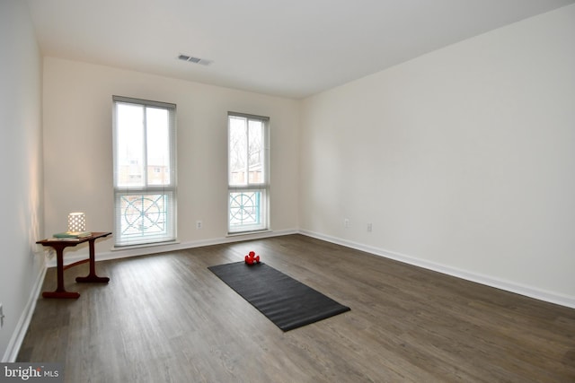 exercise room with baseboards, visible vents, and dark wood-type flooring