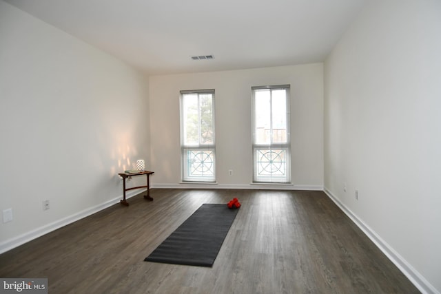 exercise room with dark wood-type flooring, visible vents, and baseboards