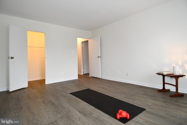 interior space with a walk in closet, baseboards, and wood finished floors