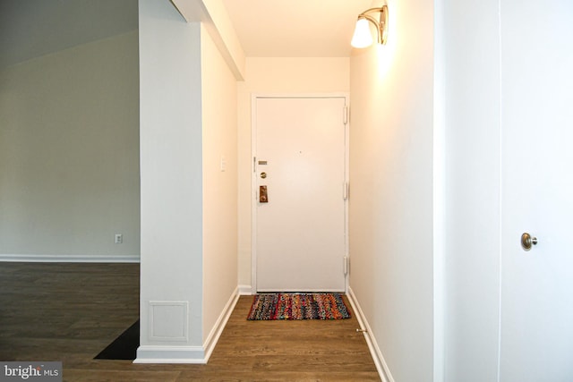 doorway featuring baseboards and wood finished floors