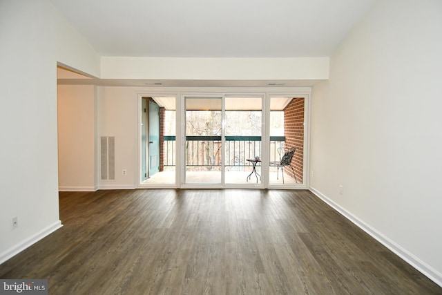 spare room with dark wood-type flooring, visible vents, and baseboards