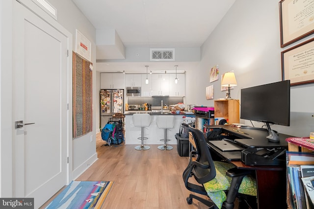 office area with light wood-type flooring and sink