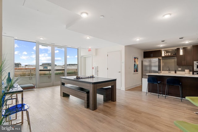 rec room featuring light hardwood / wood-style floors, floor to ceiling windows, and sink