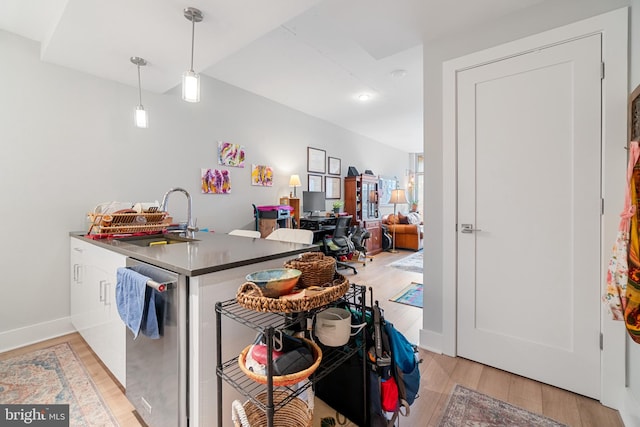 kitchen featuring dishwasher, sink, kitchen peninsula, pendant lighting, and light wood-type flooring