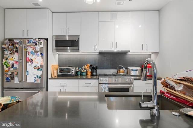 kitchen featuring decorative backsplash, stainless steel appliances, and white cabinetry