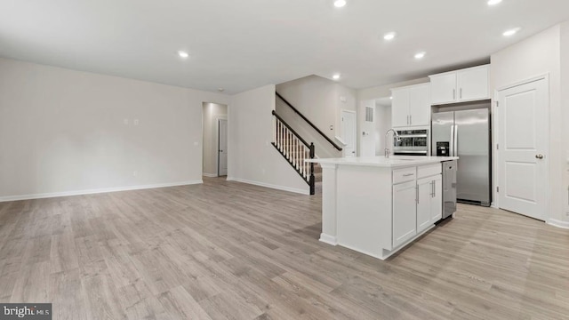 kitchen with sink, stainless steel appliances, an island with sink, light hardwood / wood-style floors, and white cabinets