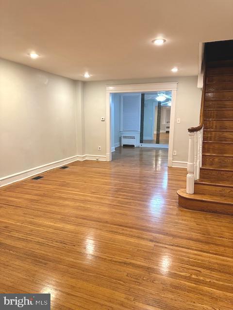 unfurnished living room featuring radiator heating unit and wood-type flooring