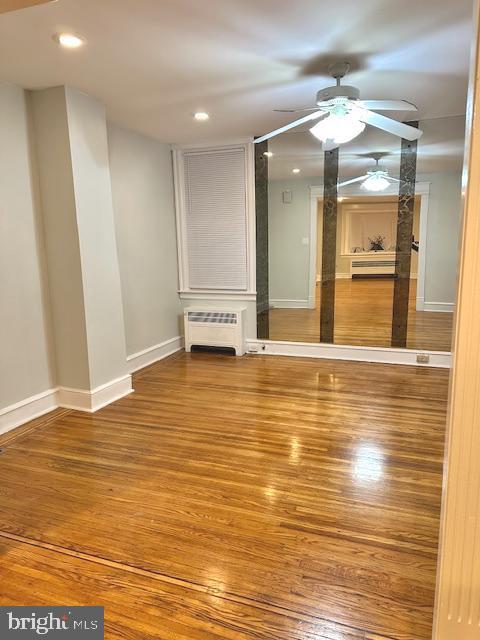 unfurnished living room with hardwood / wood-style floors, radiator, and ceiling fan