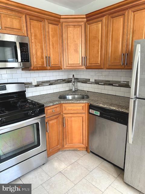 kitchen featuring light tile patterned flooring, appliances with stainless steel finishes, tasteful backsplash, and sink