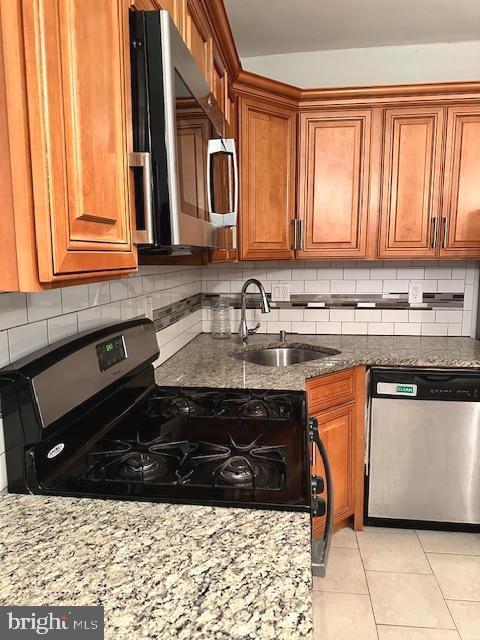 kitchen with decorative backsplash, sink, dark stone counters, and appliances with stainless steel finishes