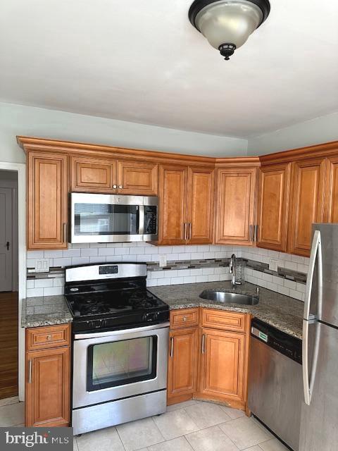 kitchen featuring decorative backsplash, light tile patterned floors, stainless steel appliances, and sink