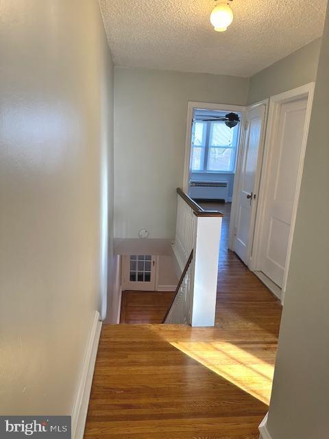 corridor featuring a textured ceiling and hardwood / wood-style flooring