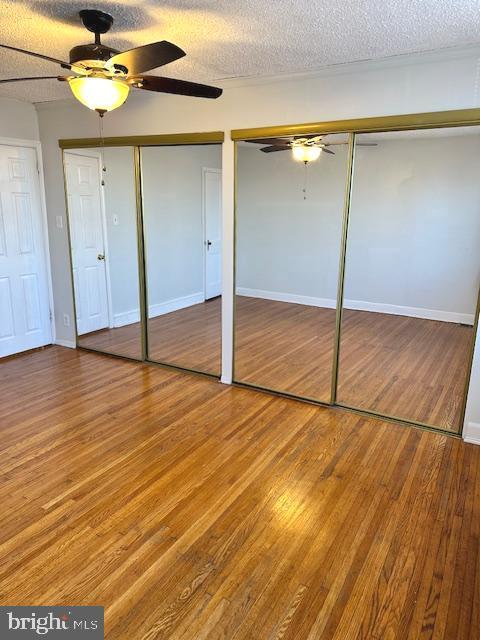 unfurnished bedroom with a textured ceiling, hardwood / wood-style flooring, and ceiling fan