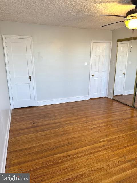 empty room featuring ceiling fan, hardwood / wood-style floors, and a textured ceiling