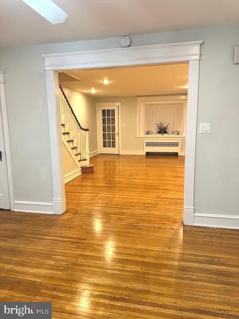 hallway featuring radiator heating unit and hardwood / wood-style flooring