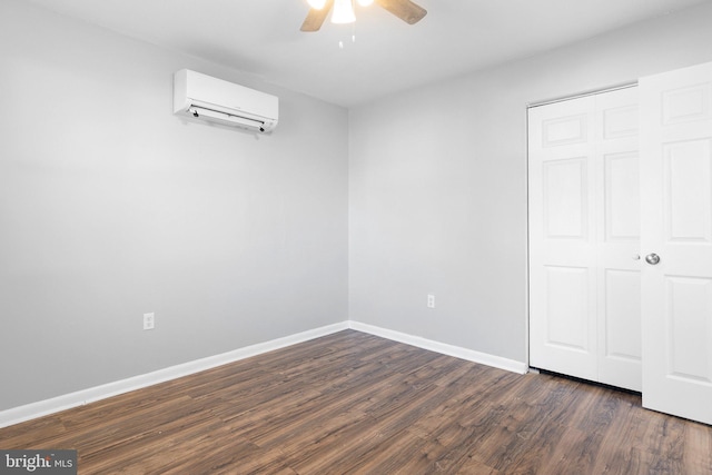 unfurnished bedroom with a wall mounted AC, a closet, ceiling fan, and dark wood-type flooring