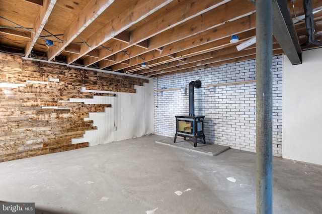 basement with a wood stove and brick wall