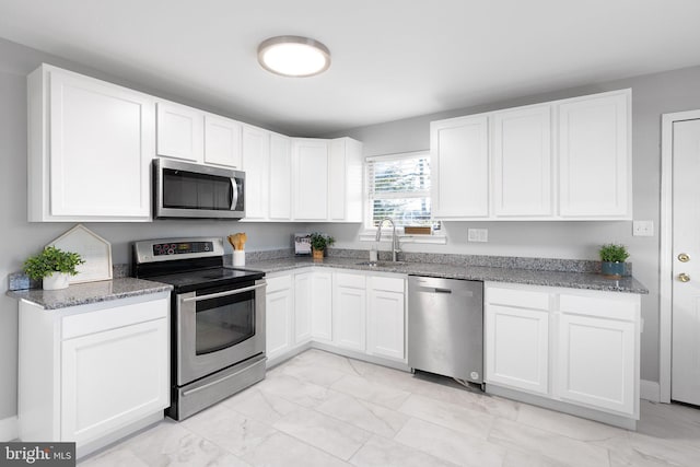 kitchen with dark stone countertops, sink, white cabinets, and appliances with stainless steel finishes