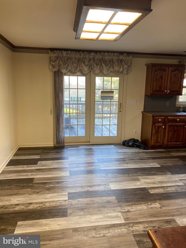 unfurnished dining area featuring crown molding and dark wood-type flooring