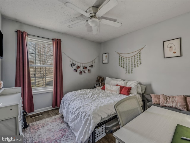 bedroom featuring ceiling fan, dark hardwood / wood-style flooring, and a textured ceiling