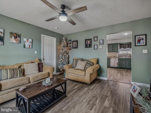 living room featuring hardwood / wood-style floors, ceiling fan, sink, and a textured ceiling