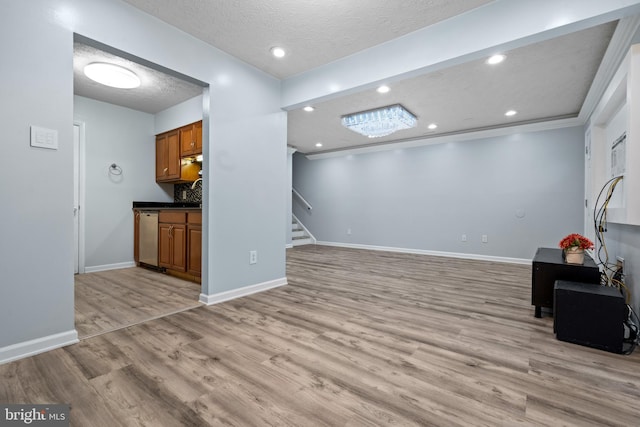 unfurnished living room with a textured ceiling, light hardwood / wood-style flooring, and crown molding