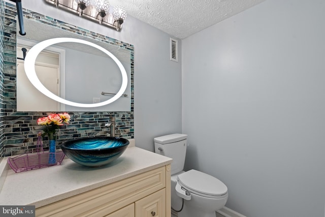 bathroom with decorative backsplash, vanity, a textured ceiling, and toilet