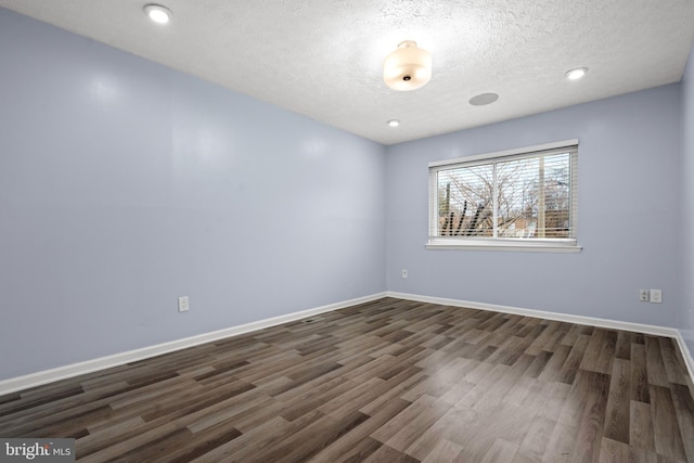 empty room featuring a textured ceiling and dark wood-type flooring