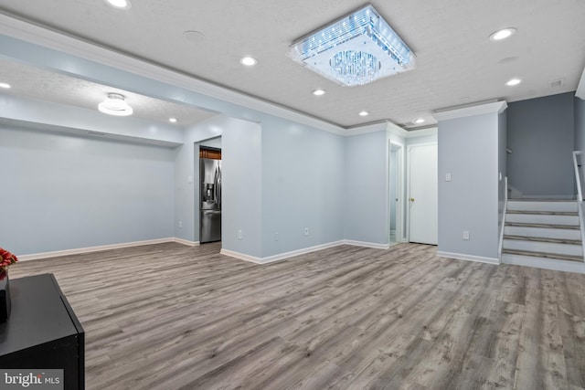 basement featuring stainless steel refrigerator with ice dispenser, a chandelier, a textured ceiling, light hardwood / wood-style floors, and ornamental molding