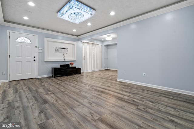 entryway featuring wood-type flooring, ornamental molding, and a textured ceiling