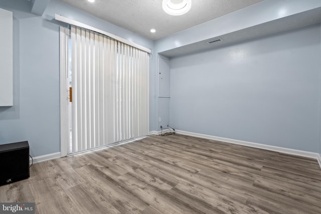 spare room featuring wood-type flooring and a textured ceiling