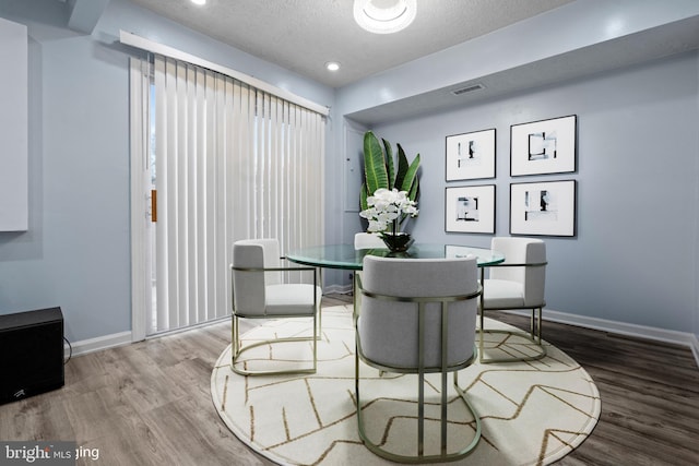 dining room featuring wood-type flooring and a textured ceiling