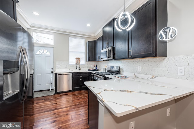 kitchen featuring sink, light stone countertops, appliances with stainless steel finishes, decorative light fixtures, and dark hardwood / wood-style flooring