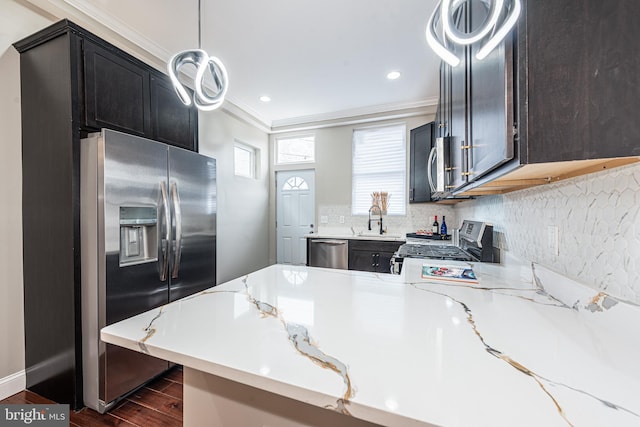 kitchen with kitchen peninsula, appliances with stainless steel finishes, dark wood-type flooring, sink, and hanging light fixtures