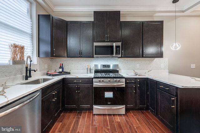 kitchen featuring sink, hanging light fixtures, dark hardwood / wood-style floors, ornamental molding, and appliances with stainless steel finishes