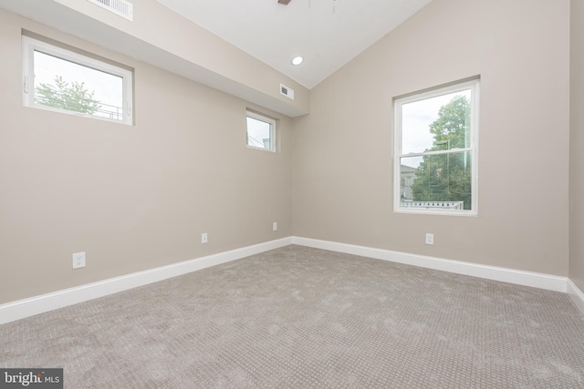 empty room featuring a wealth of natural light, light carpet, and vaulted ceiling